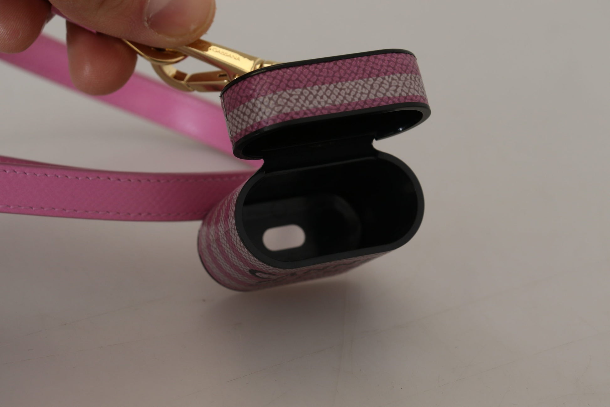 Étui Airpods en cuir rose et noir avec logo doré en métal.