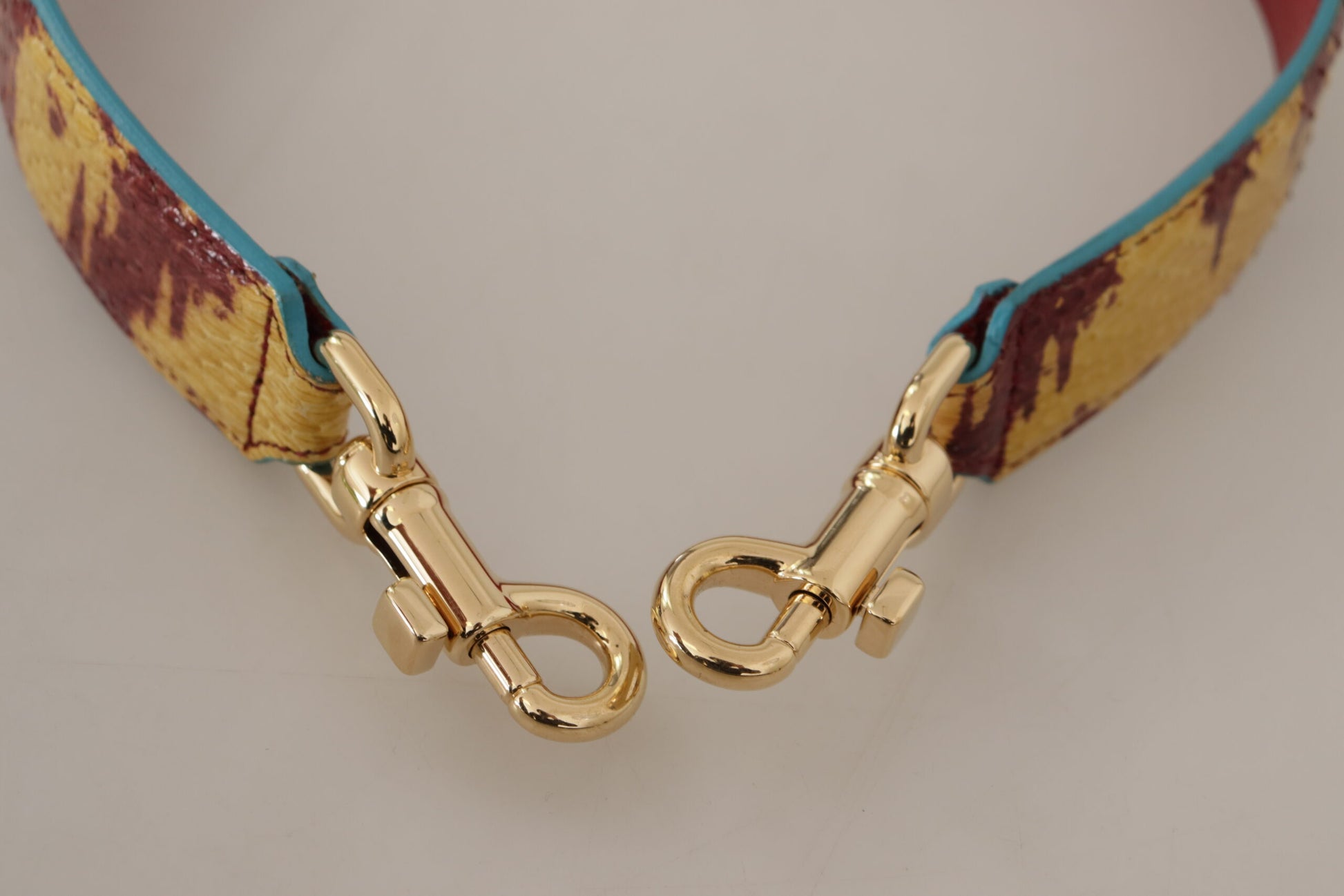 Bandoulière en cuir jaune et rouge avec détail doré.