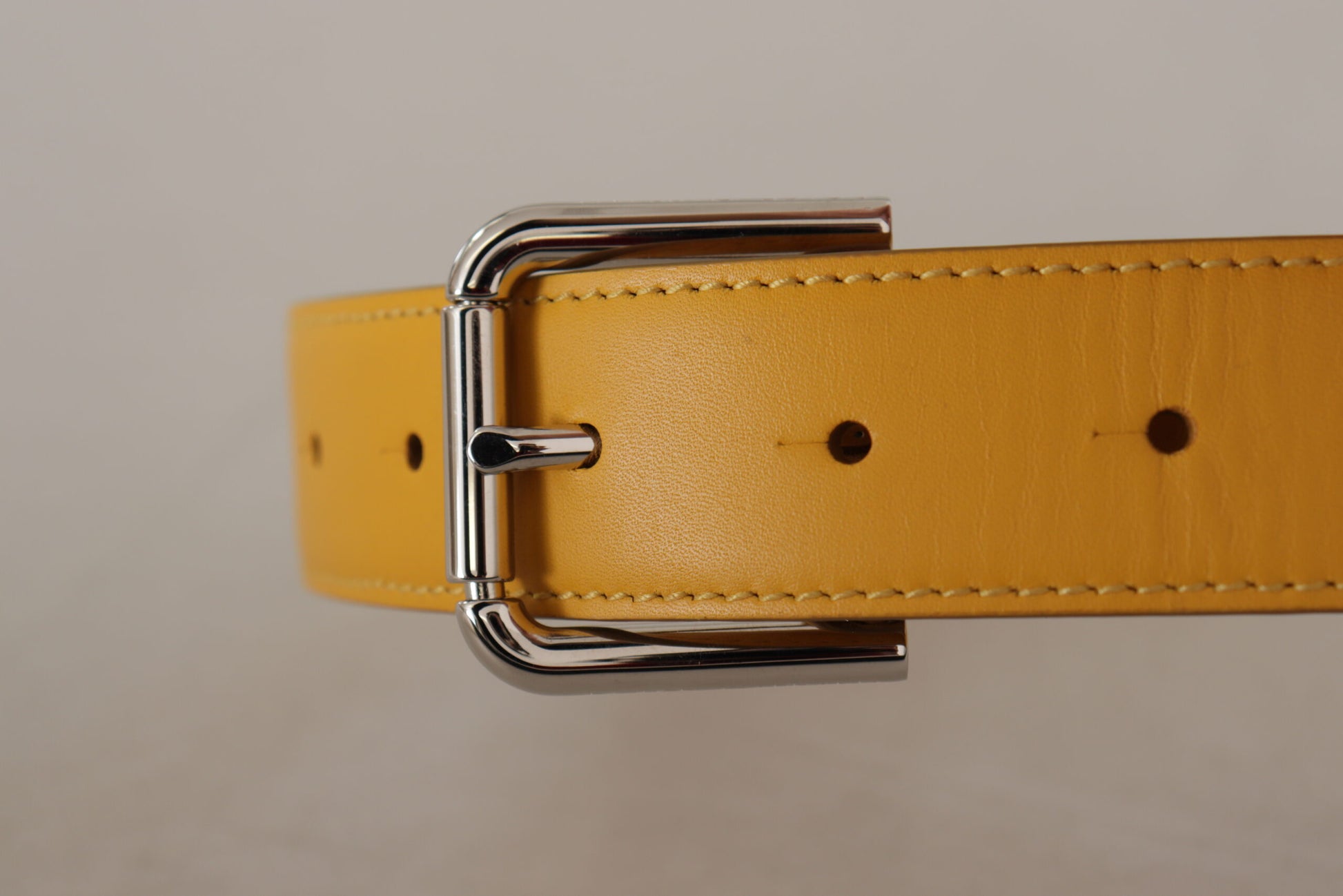 Ceinture en cuir jaune avec boucle en métal argenté et logo.