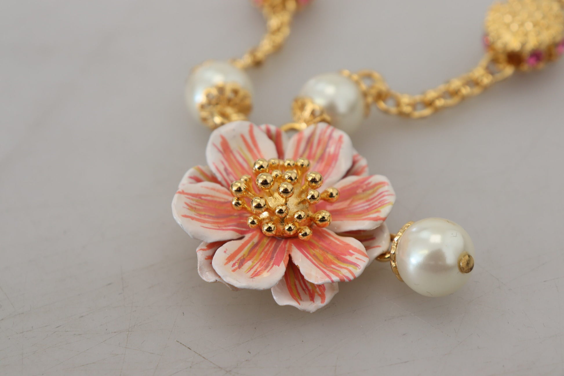 Collier doré à motifs floraux, ornements roses et cristaux.