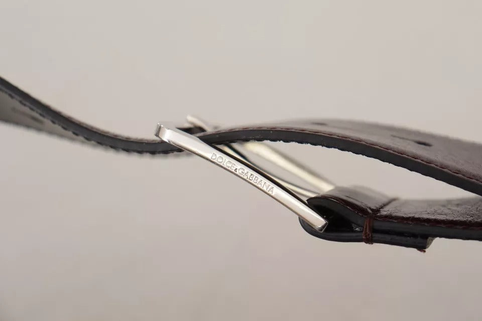 Ceinture en cuir marron foncé avec boucle en métal gravée du logo.