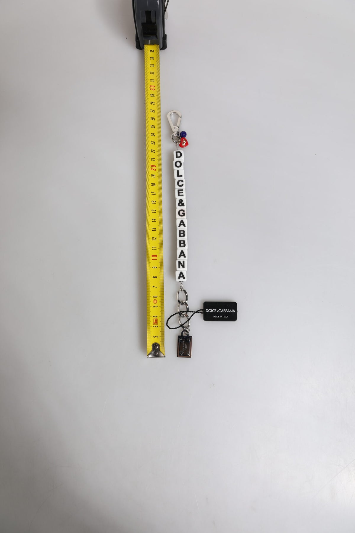 Bracelet en chaîne en laiton argenté avec logo et breloques décoratives.