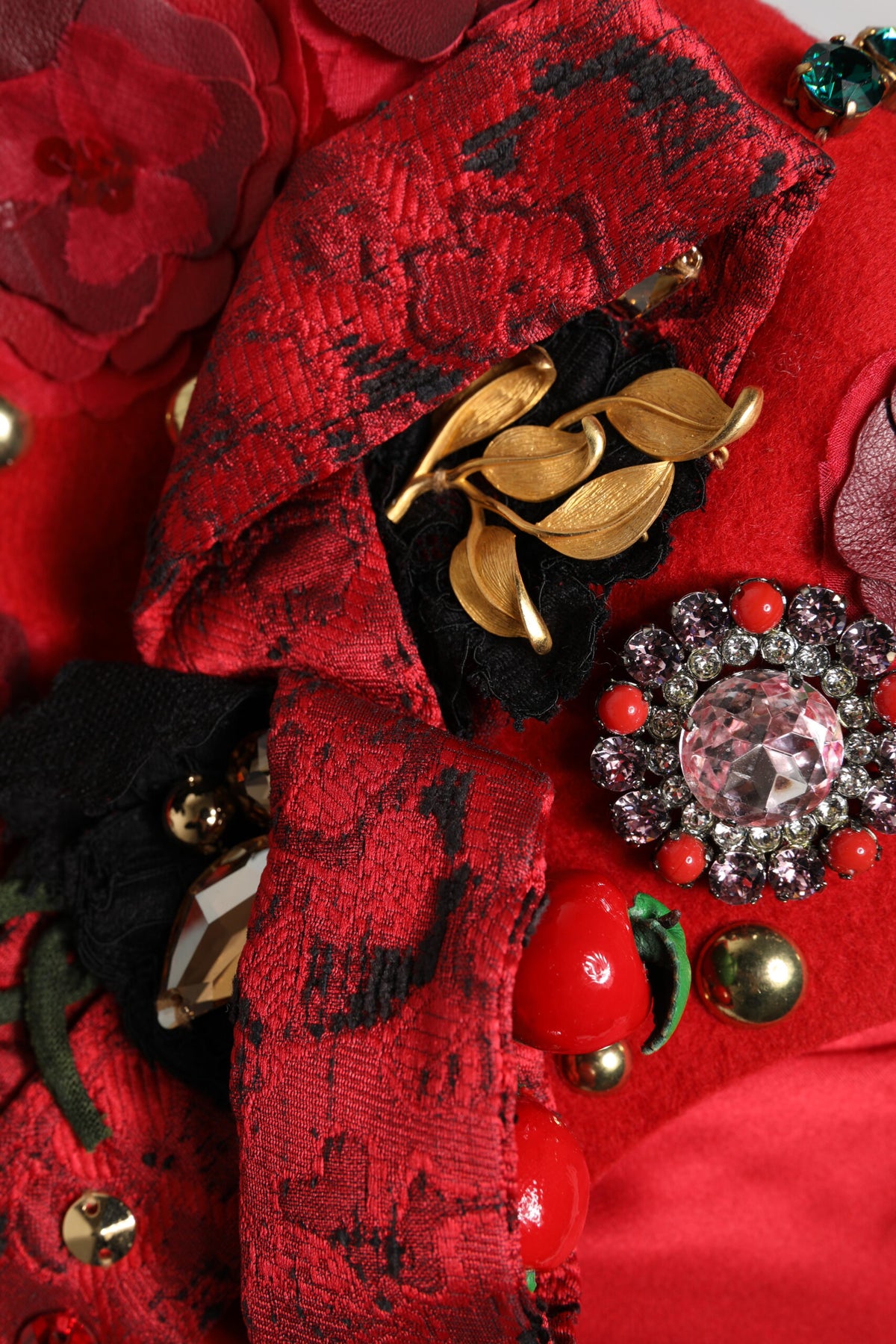 Chapeau décoré d'une broche en forme de roses dorées et de cristaux rouges.