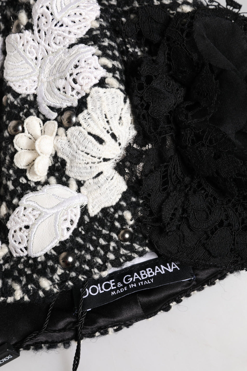 Chapeau cloche en laine noire avec décor floral blanc.