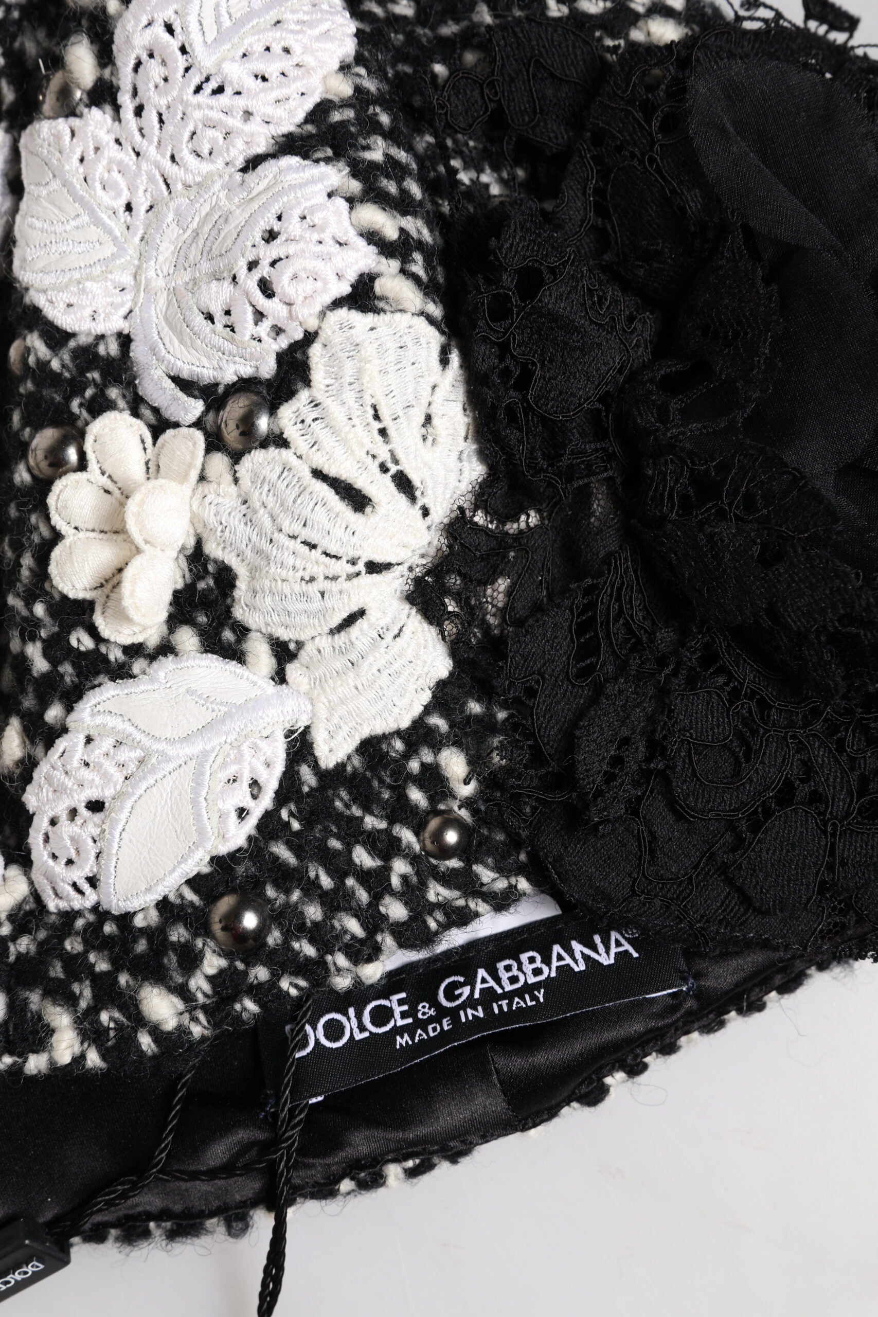 Chapeau cloche en laine noire avec décor floral blanc.