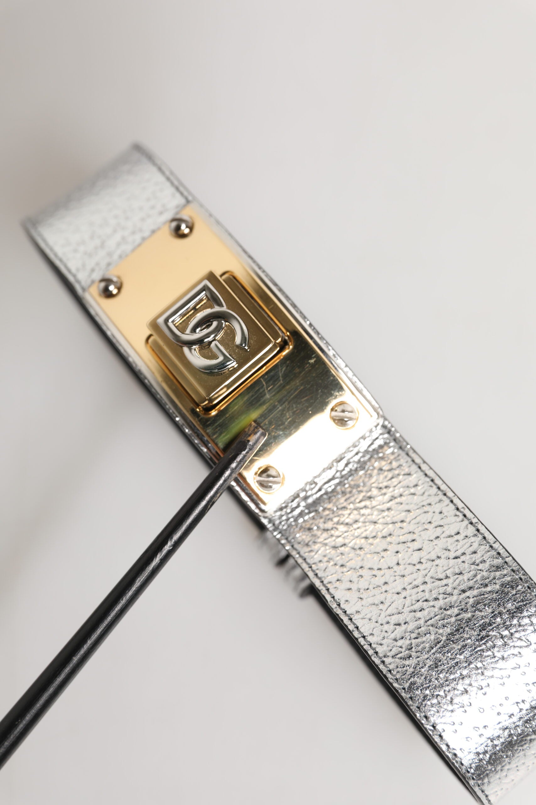 Collier en cuir texturé argenté avec détail métallique doré.